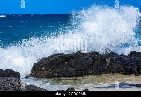 Waves crashing and splashing on lava rock along the shore of Kaupo Cove; Oahu, Hawaii, United States of America Stock Photo