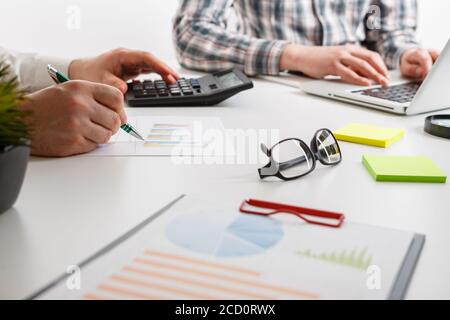 Documents with chart and graph and pen on background of two employees working Stock Photo