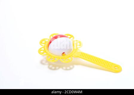 Yellow plastic rattle for a baby in the form of a flower with a handle on a white background Stock Photo