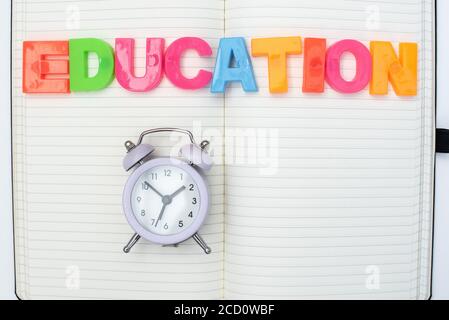 Colored plastic letters of the English alphabet, alarm clock and a notebook on a white background. Children education Stock Photo
