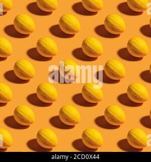 Seamless pattern of whole ripe honeydew melon over a bright yellow background. Fresh fruit summer and autumn print. Shot with hard light. Flat lay. Stock Photo