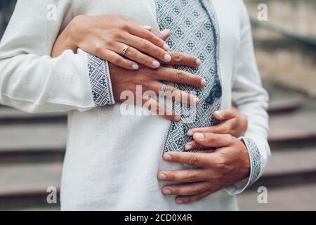 Wedding newlyweds couple wearing rings on fingers. Bride and groom wear traditional embroidered ukrainian shirts. Stock Photo