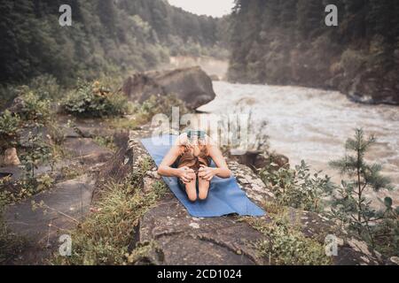 A blonde woman practices yoga on nature Stock Photo