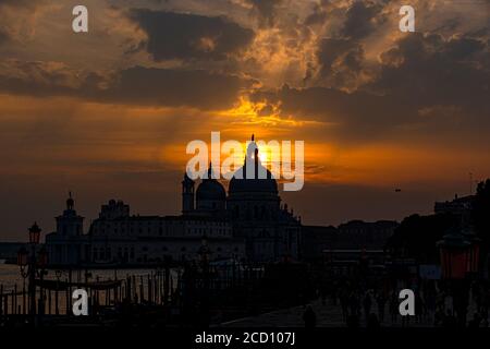 Silhouette of Santa Maria della Salute backlight, with the sky with fiery clouds reflecting in the lagoon Stock Photo