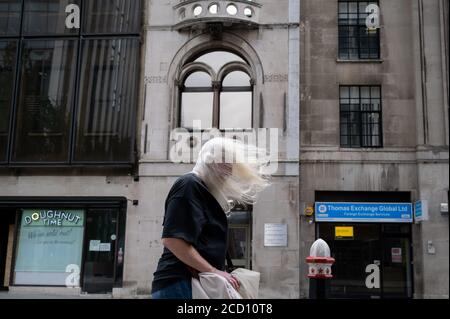 As the Met Office issued alerts for very strong winds across southern England and Wales, a weather system named Storm Francis, a middle-aged man's white hair blows forward to partially obscure his eyesight while walking along Fenchurch Street in the City of London, the capital's financial district, on 25th August 2020, in London, England. Stock Photo