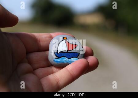 Closeup of a man holding a painted hiking stone left on the walking path Stock Photo