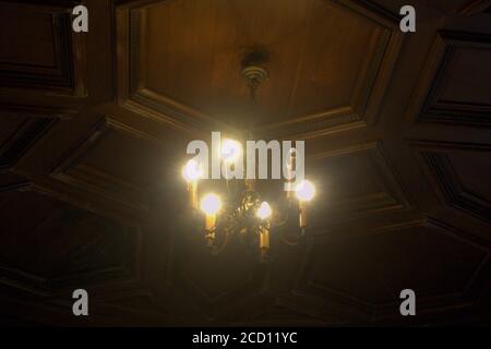 A small chandelier beneath a wooden hexagonal ceiling Stock Photo