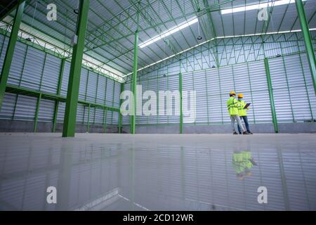 Asian Industrial Engineer in Hard Hat Wearing Safety Jacket plan work with warehouse workers Processes in the factory. Stock Photo