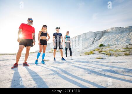 Group of runners standing outdoors before trail running training. Low wide angle view with long shadows Stock Photo