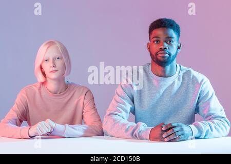 serious young multiethnic couple sitting at table and looking at camera, students listening to the lecture, puround, business, job, profession, robot, Stock Photo