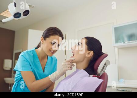 Woman doctor dentist looking at open woman patients mouth and examining her teeth in dental clinic Stock Photo