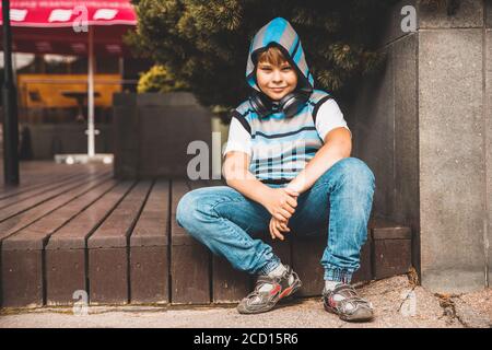 joyful young boy in striped sweater sits on the steps Stock Photo