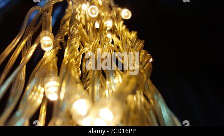 Close up lights of garland on the wall. Glowing electric garland on a black background. Stock Photo