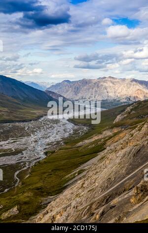 View from mountaintop of the braided Marsh Fork River and surrounding mountains, with sun hitting a mountain in the background, on a sunny summer d... Stock Photo