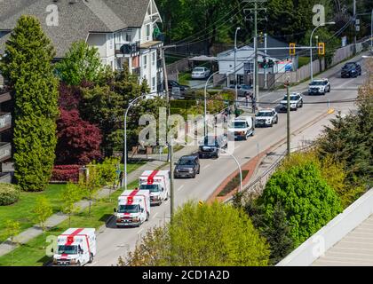 High angle view of emergency situation with a line-up of ambulances and police cars on a residential street in a neighborhood in Surrey Stock Photo