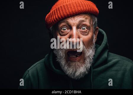 Stunned scared bearded old-aged male model open mouth with one missing tooth widely being surprised and shocked with news Stock Photo
