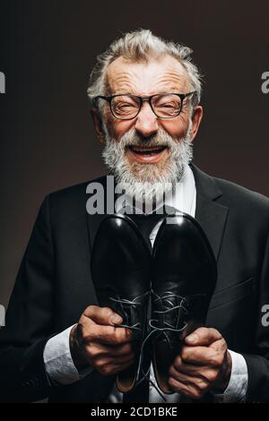 Happy transformation of a poor homeless old tramp into a well-dressed gentleman in suit who is beaming with joy and hapiness enjoying his new leather Stock Photo