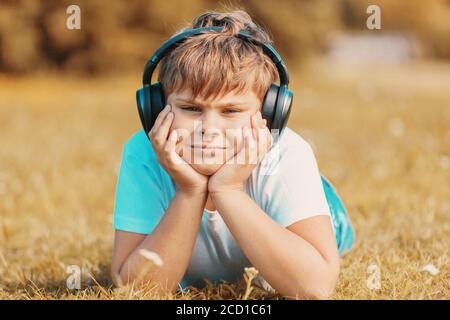 boy with headphones listening to music lying on the grass in the park Stock Photo