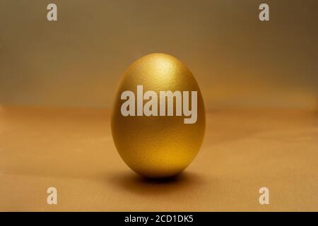 A Gold egg on at golden the background Stock Photo