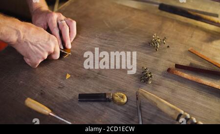 Tanner cuts out leather goods by cutter. Craftsman works by knife in workshop. Stock Photo