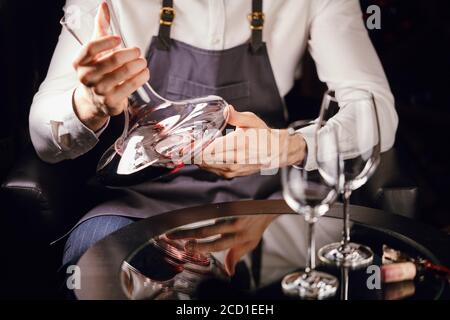Skilled sommelier pouring wine from decanter into wine glass. Degustation of wine process in wine boutique, close up. Stock Photo