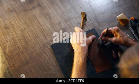 Small business concept with copy space. Man holding crafting tool and working. Craftsman in tannery. Stock Photo