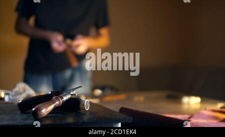 Cropped portrait of craftsman working with leather in tannery workshop. Small business concept, copy space. Stock Photo