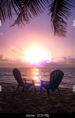 Two beach chairs with magnificent sunset and palm trees Stock Photo