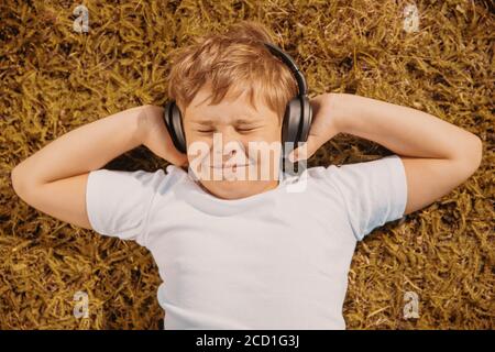 handsome boy with headphones listening to music lying on the grass Stock Photo