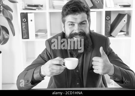 My energy. Man handsome boss sit in office drinking coffee. Comfy workspace. Good morning. Bearded hipster formal suit relaxing with coffee. Office life routines. Respectable ceo. First coffee. Stock Photo