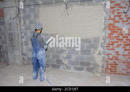 Machine application of plaster to the wall. Plasterer spraying plaster on wall. Professional, painting. Plastering walls in a new building Stock Photo