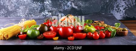 various colorful tomatoes and basil leaves on rustic table. fresh delicious zebra tomato and ccor de boeuf Stock Photo