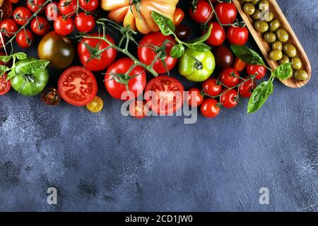 various colorful tomatoes and basil leaves on rustic table. fresh delicious zebra tomato and ccor de boeuf Stock Photo