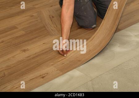Worker installing new parquet vinyl tiles on floor Stock Photo