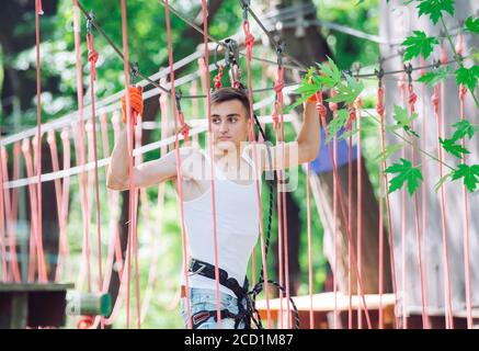 Man spend their leisure time in a ropes course. Man engaged in rope park. Stock Photo