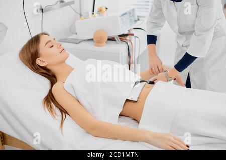 young female lying on bed treating stomach disease, beautiful caucasian woman in hospital