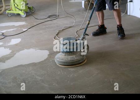 High angle shot of a worker grinding the floor using a single disc machine. Stock Photo