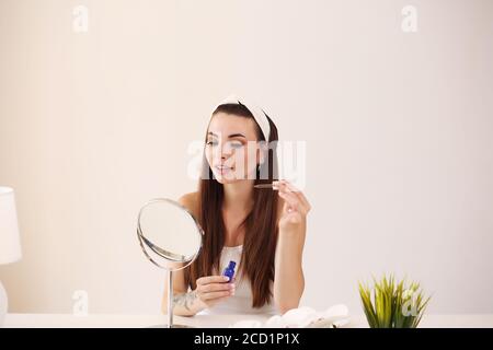 Beauty, skincare and people concept - smiling young girl suggesting beauty for on face in room Stock Photo