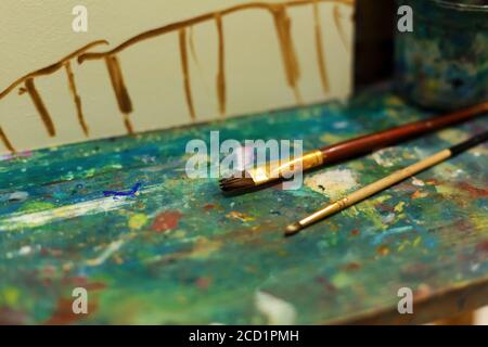 Brushes on an easel stained with paints in the artist's studio. Stock Photo