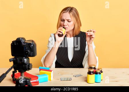 Popular dietitian female blogger sniffing new bottle with health and beauty food supplement, frowning in disgust, it smeels like expired and spoiled o Stock Photo