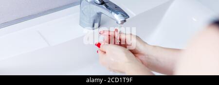 Washing woman hands with streaming water under tap in bathroom,washing hands in a white basin with a bar,Hygiene,Hand washing,Woman washing hands Stock Photo