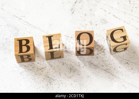 Four wooden cubes with word BLOG on white working board. Stock Photo