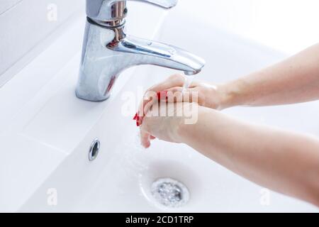 Washing woman hands with streaming water under tap in bathroom,washing hands in a white basin with a bar,Hygiene,Hand washing,Woman washing hands Stock Photo