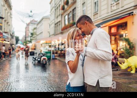 Young people in love walk in old Lviv city wearing traditional ukrainian shirts. Couple dance by cafes after rain Stock Photo