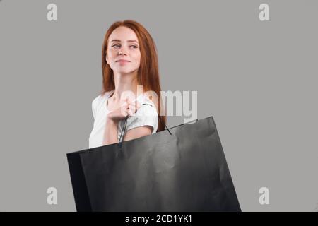 red-haired girl with shopping bags walking . close up photo. gray background, studio shot, hobby, lifestyle, weekend, day for shopping , day off