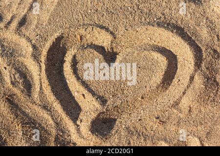 Heart on the sand as a symbol of love. The view from the top on the hot sand. Hand-drawn heart shape on the beach. Love and unity. Dreams of the sea a Stock Photo