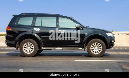 The car goes on the highway on a background of blue sky. An SUV is driving on a motion blurred road. Stock Photo