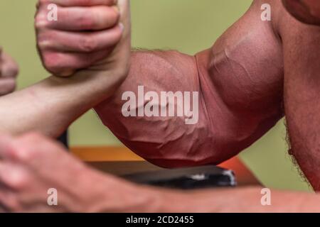 Close-up shot of a strong man's muscles during an arm-wrestling fight