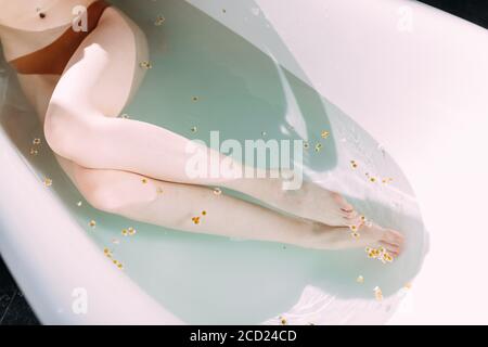 Cropped Female owner of slim long legs with white untanned skin taking bath during Spa treatment in hotel well-being area. Stock Photo