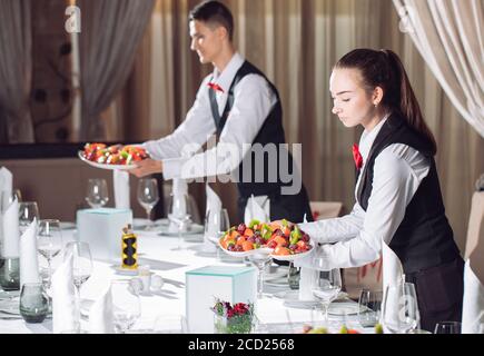 Waiters serving table in the restaurant preparing to receive guests Stock Photo